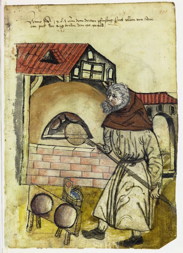 A baker slides a round loaf into a domed brick oven with a long-handled peel, with more loaves stacked on racks nearby.